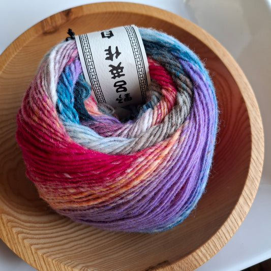 Multicolored skein of yarn in a wooden bowl