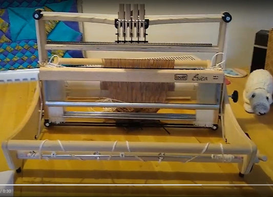 An Erica 4 shaft loom, 50cm wide, displayed on a table, showing the heddles and shafts